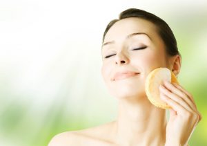 A woman cleansing her face with a sponge