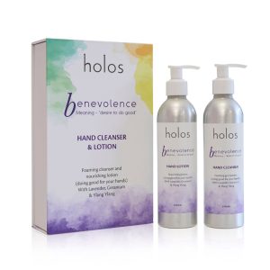 The image showcases Holos Skincare's Benevolence Hand Cleanser & Lotion Gift Set, featuring two pump bottles and a box. The packaging boasts colorful gradients and highlights the foaming cleanser and nourishing lotion infused with lavender and ylang-ylang.